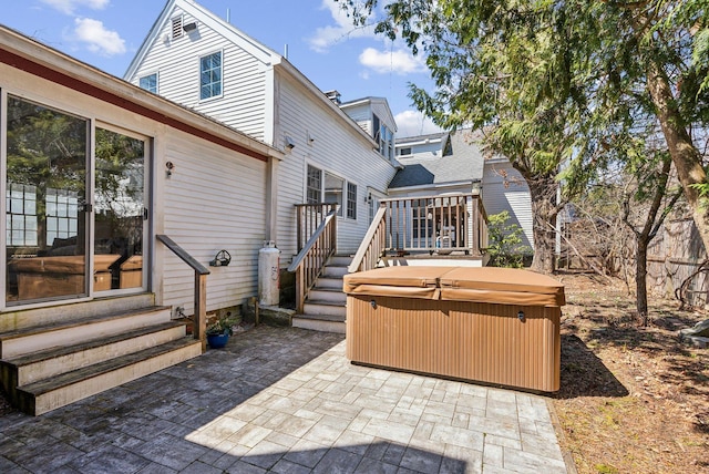 rear view of house with a wooden deck, entry steps, a hot tub, and a patio