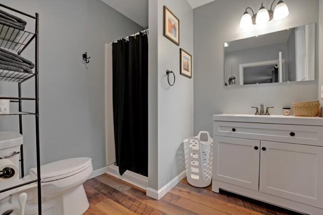 8 College Ave, Gorham, ME 04038 - full bath with wood finished floors, toilet, curtained shower, vanity, and baseboards
