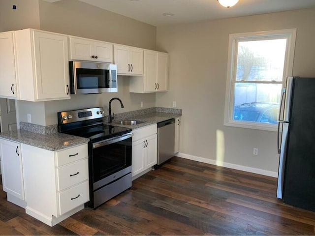 8 College Ave, Gorham, ME 04038 - kitchen with stainless steel appliances, a sink, baseboards, light stone counters, and white cabinetry
