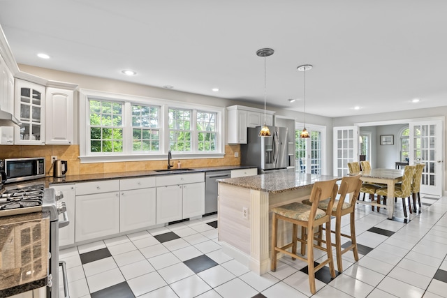 10 Thistleberry Ln, York, ME 03909 - kitchen with stainless steel appliances, dark stone countertops, decorative backsplash, white cabinets, and a breakfast bar