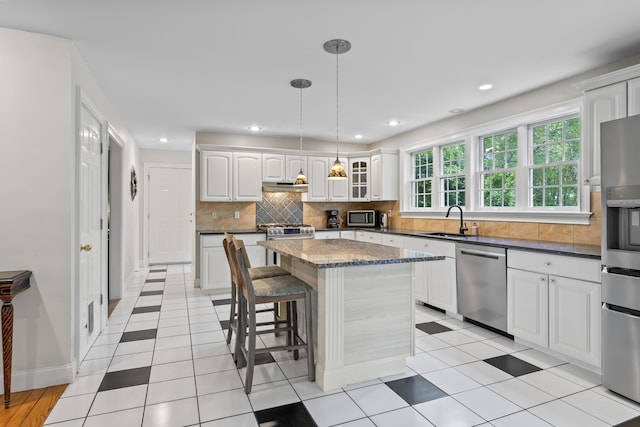 10 Thistleberry Ln, York, ME 03909 - kitchen with appliances with stainless steel finishes, tasteful backsplash, white cabinetry, a breakfast bar area, and a center island
