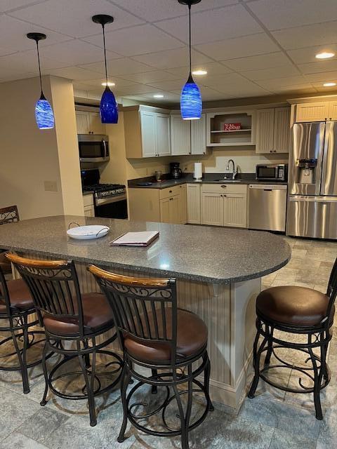 8 Prince St, Lincoln, ME 04457 - kitchen featuring dark countertops, open shelves, a sink, stainless steel appliances, and a kitchen bar