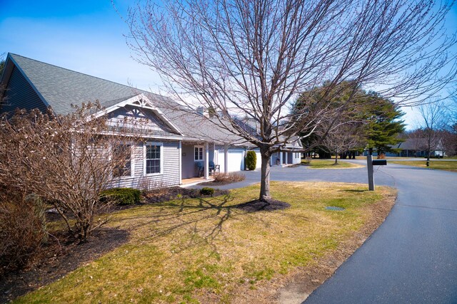 view of front of house with a shingled roof, driveway, and a front lawn