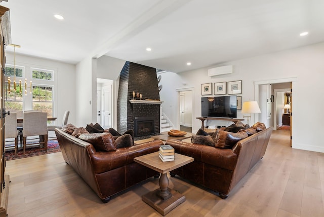 239 Hunter Way, Falmouth, ME 04105 - living room with a wall mounted AC, a brick fireplace, light wood-style floors, recessed lighting, and baseboards