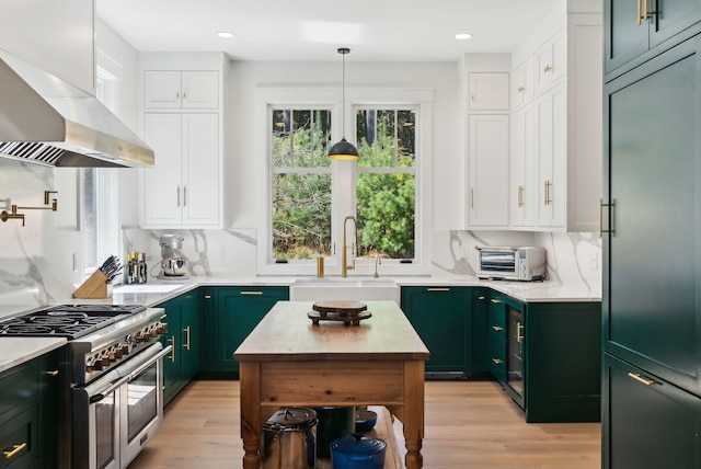 239 Hunter Way, Falmouth, ME 04105 - kitchen with green cabinetry, wall chimney range hood, range with two ovens, a sink, and white cabinetry
