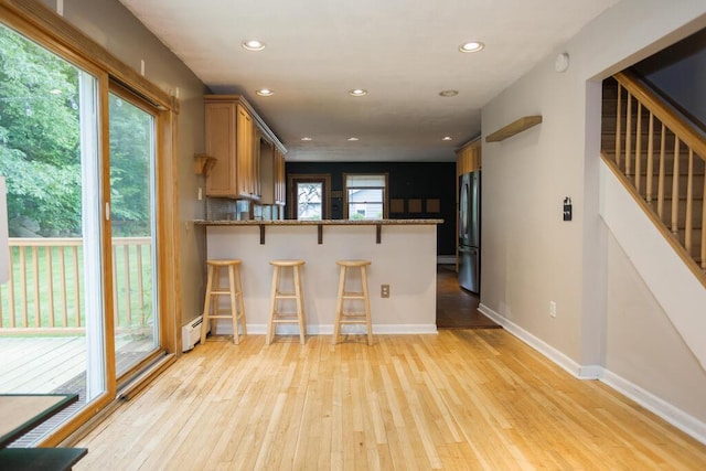 23 Orr St, Wilton, ME 04294 - kitchen with freestanding refrigerator, baseboard heating, light wood finished floors, a breakfast bar, and recessed lighting