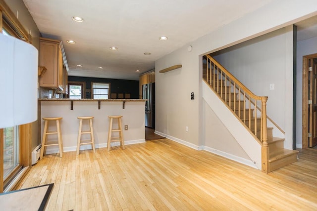 23 Orr St, Wilton, ME 04294 - kitchen featuring freestanding refrigerator, a baseboard radiator, a breakfast bar, light wood-style flooring, and recessed lighting