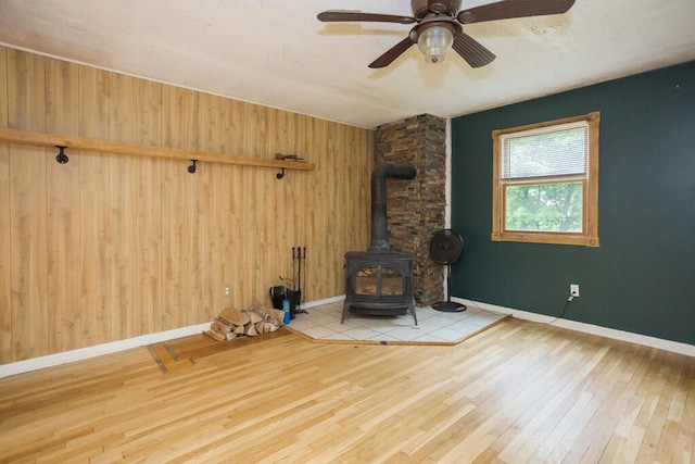 23 Orr St, Wilton, ME 04294 - unfurnished room with a wood stove, wood-type flooring, wood walls, and a ceiling fan