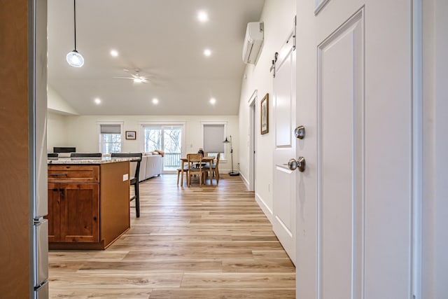 15 Summit Dr, Bridgton, ME 04009 - kitchen featuring a kitchen bar, brown cabinetry, light wood finished floors, a wall unit AC, and lofted ceiling