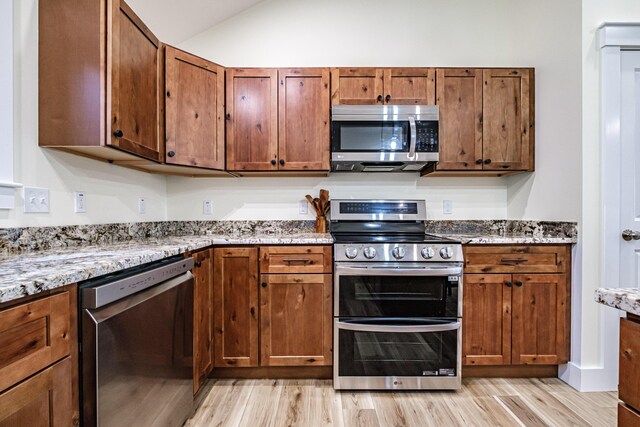 15 Summit Dr, Bridgton, ME 04009 - kitchen with light wood-style flooring, light stone countertops, vaulted ceiling, and stainless steel appliances