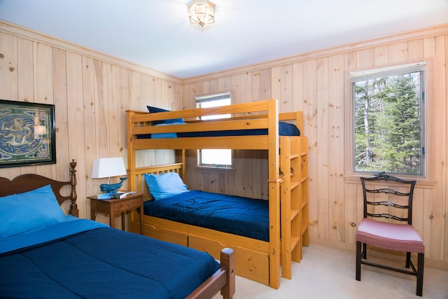 bedroom featuring wooden walls, multiple windows, and carpet