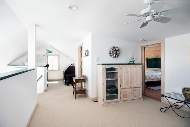 living area featuring ceiling fan, light colored carpet, baseboards, an upstairs landing, and lofted ceiling
