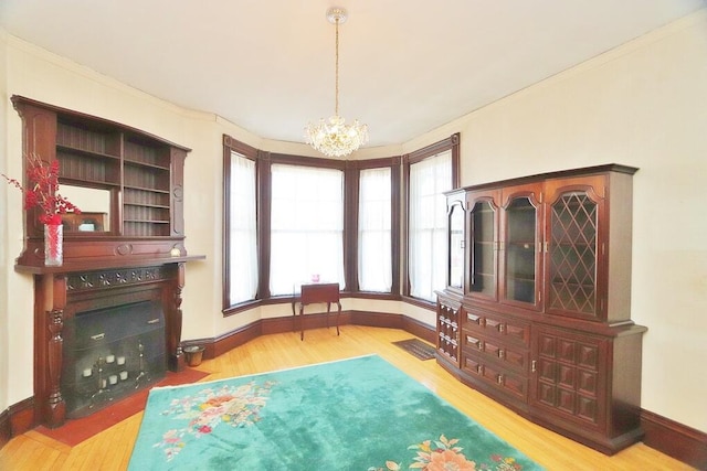 living area featuring baseboards, wood finished floors, an inviting chandelier, and crown molding