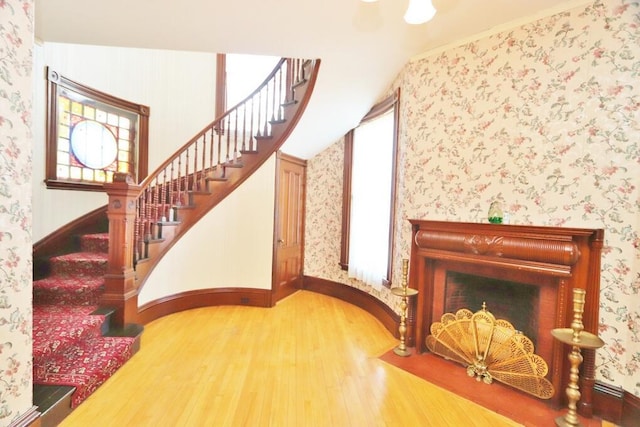 interior space with wallpapered walls, wood finished floors, baseboards, and vaulted ceiling