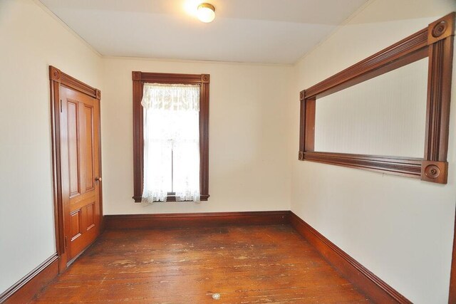 empty room featuring hardwood / wood-style flooring, baseboards, and crown molding