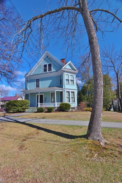 view of front of house featuring a chimney, a front yard, and covered porch