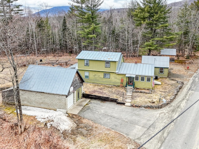 exterior space with metal roof, a garage, a mountain view, and driveway