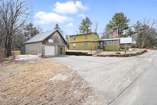 view of front facade with an outbuilding, aphalt driveway, and a detached garage