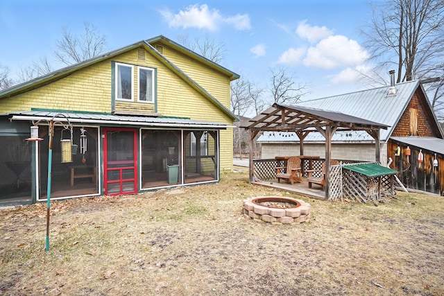 rear view of house featuring metal roof, a gazebo, a sunroom, and a fire pit