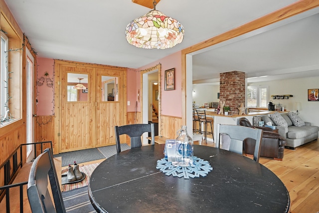 dining room featuring wooden walls, a wainscoted wall, and wood finished floors