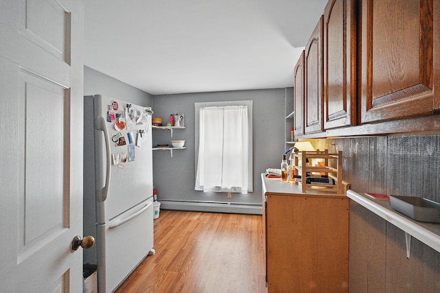 kitchen featuring light wood finished floors, freestanding refrigerator, open shelves, baseboard heating, and light countertops