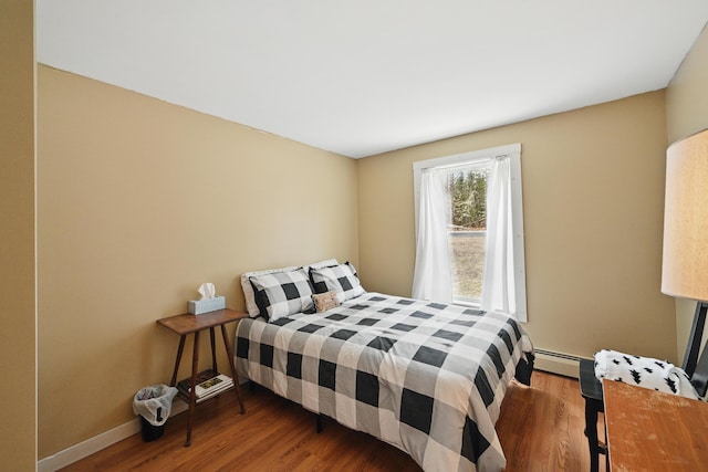 bedroom featuring a baseboard radiator, baseboards, and wood finished floors