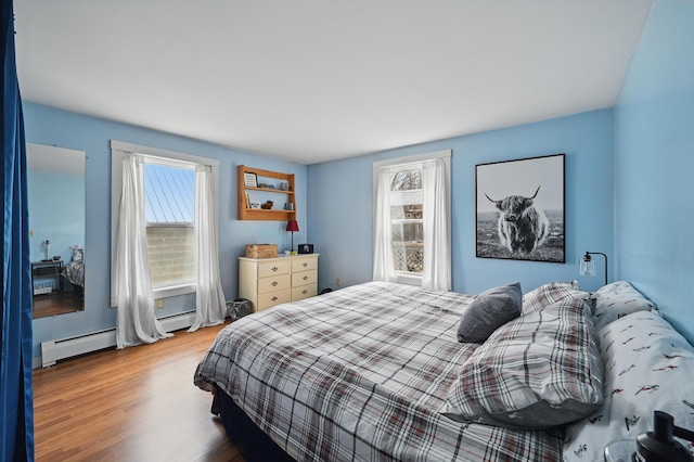 bedroom featuring a baseboard heating unit, baseboard heating, and wood finished floors