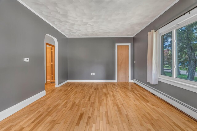 8 Sylvan Rd, Orono, ME 04473 - empty room featuring a baseboard heating unit, ornamental molding, arched walkways, and light wood-type flooring