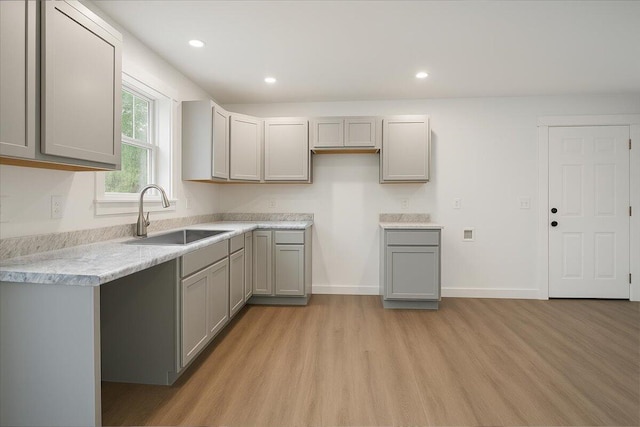 kitchen with gray cabinetry, recessed lighting, a sink, and light wood-style floors