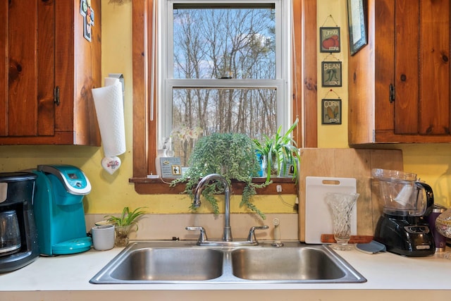 kitchen with light countertops, a sink, and brown cabinetry