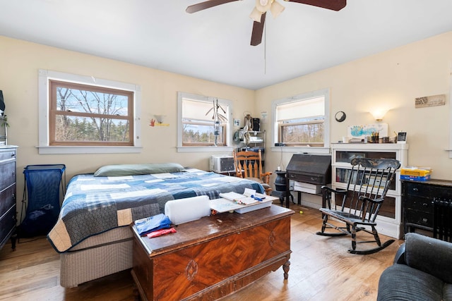 bedroom with a ceiling fan, wood finished floors, and multiple windows