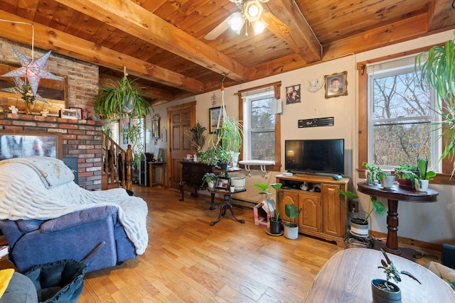 living room featuring beam ceiling, ceiling fan, light wood-type flooring, and wooden ceiling
