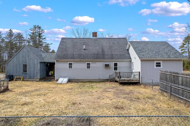 back of property featuring a chimney, a lawn, a wooden deck, fence, and a shingled roof