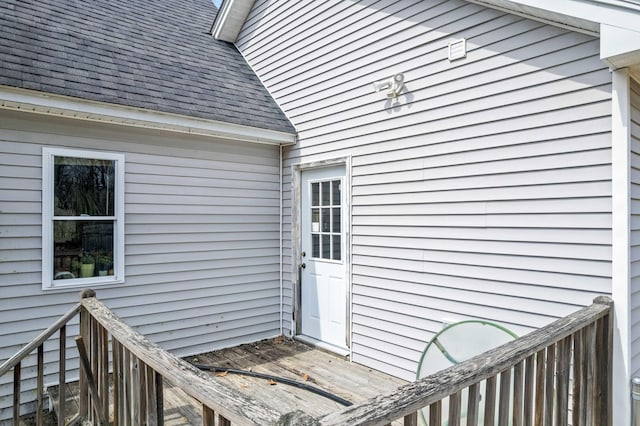 view of exterior entry with roof with shingles