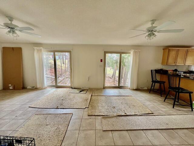 doorway featuring ceiling fan, light tile patterned floors, and a wealth of natural light