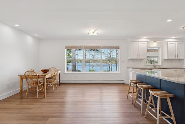 34 Jordan Shore Dr, Poland, ME 04274 - kitchen with a sink, a baseboard heating unit, light wood-type flooring, a kitchen bar, and white cabinets