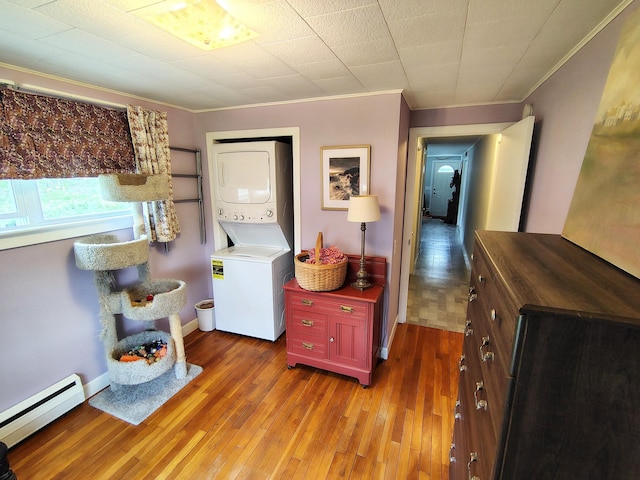 90 Whig St, Winterport, ME 04496 - laundry room featuring stacked washer and clothes dryer, a baseboard radiator, crown molding, and wood-type flooring