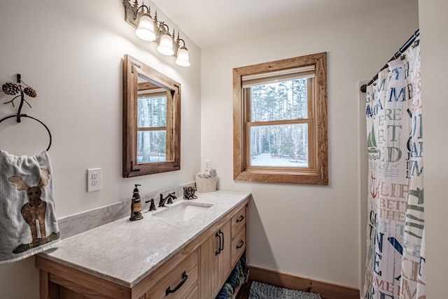full bathroom featuring a shower with shower curtain, baseboards, and vanity
