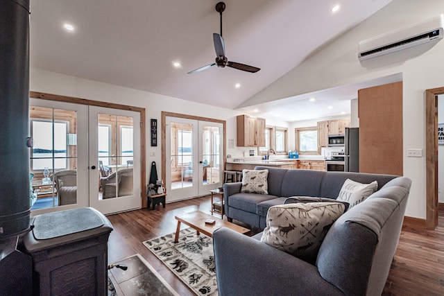 living room with french doors, a wall unit AC, dark wood finished floors, vaulted ceiling, and a ceiling fan