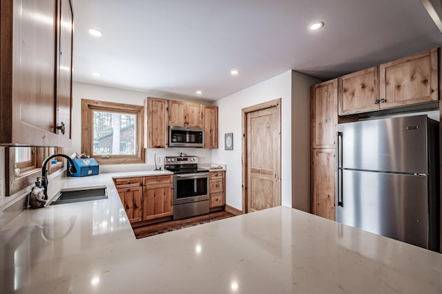 kitchen with stainless steel appliances, a sink, recessed lighting, and light stone counters