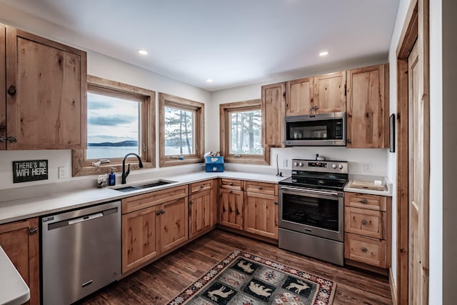 kitchen with recessed lighting, stainless steel appliances, light countertops, a sink, and dark wood-type flooring