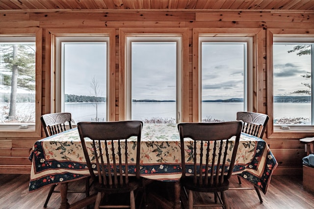 dining room featuring wood finished floors, a water view, wood walls, and wooden ceiling