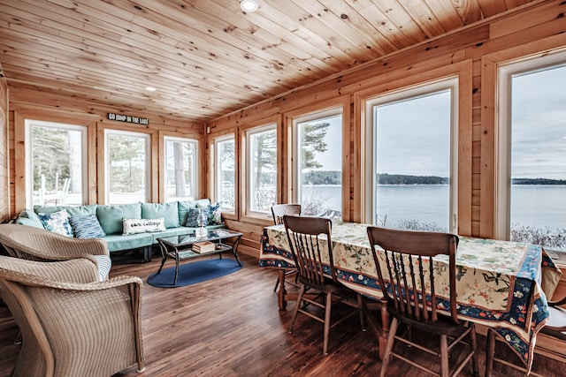 sunroom / solarium with wooden ceiling, wood finished floors, wooden walls, and a deck with water view