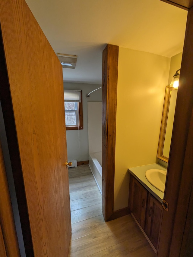 full bath featuring wood finished floors, vanity, baseboards, and shower / bath combination