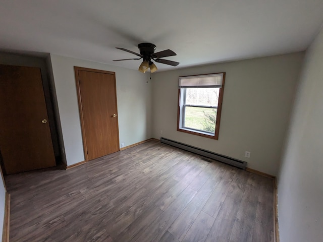 unfurnished bedroom featuring wood finished floors, ceiling fan, baseboard heating, and baseboards