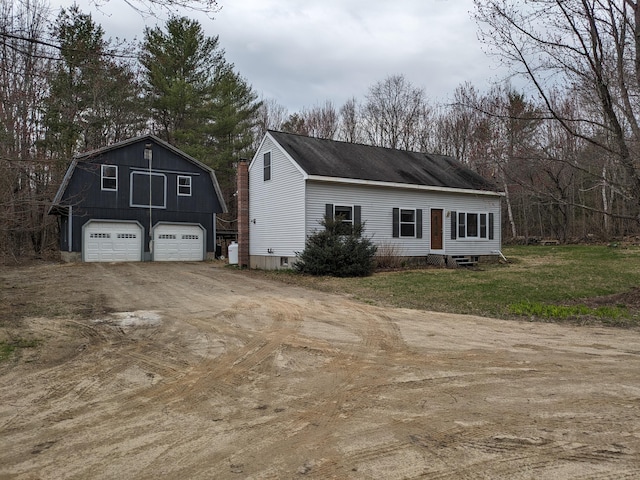 view of home's exterior with a garage, an outbuilding, a gambrel roof, and driveway