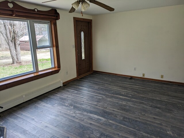 spare room with dark wood-style flooring, ceiling fan, baseboard heating, and baseboards