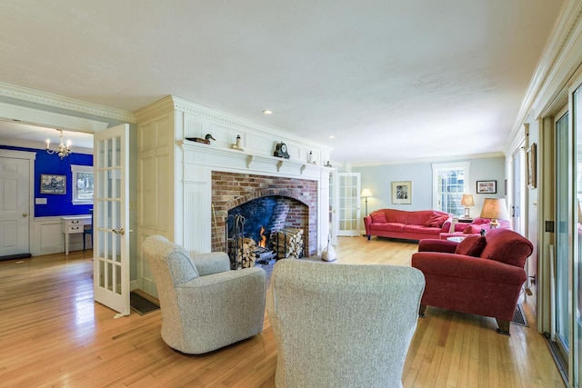 living room featuring an inviting chandelier, light wood finished floors, ornamental molding, and french doors