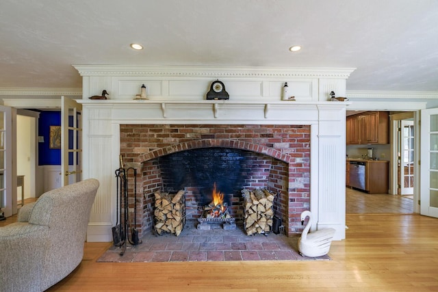 interior details with recessed lighting, wood finished floors, dishwasher, crown molding, and a brick fireplace
