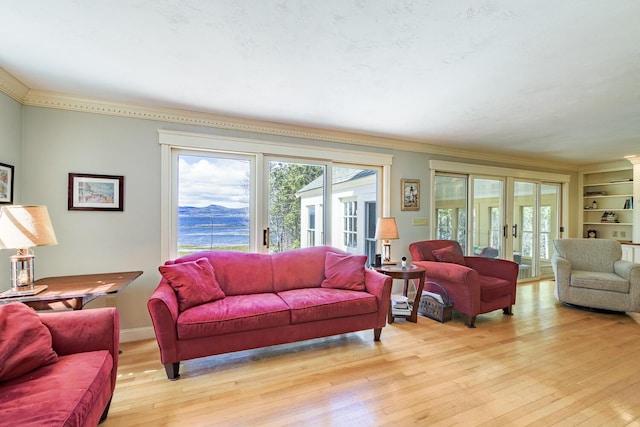 living area with a wealth of natural light, light wood finished floors, ornamental molding, and french doors